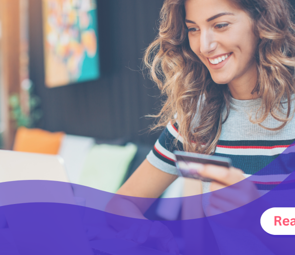 woman holding card looking at laptop