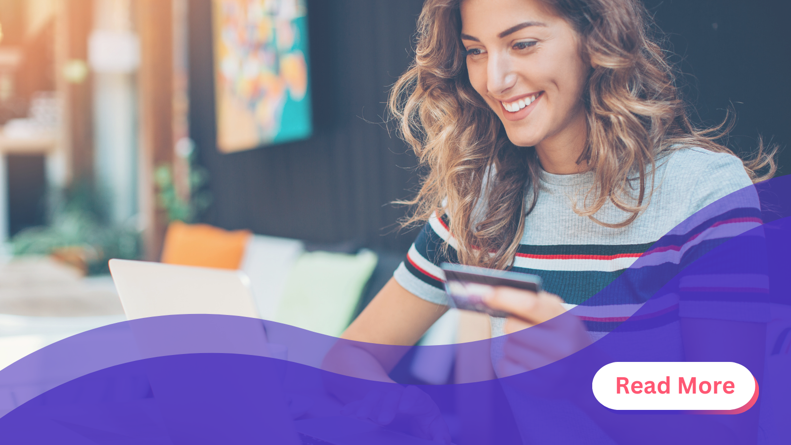 woman holding card looking at laptop